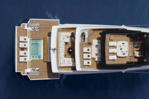 Luxurious white lounge seating and a refreshing pool adorn the expansive deck of this elegant yacht.