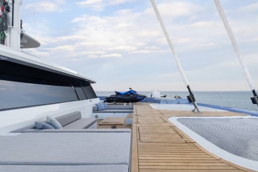 A luxurious yacht with a wooden deck, comfortable seating, and a scenic view of the ocean and sky in the background.