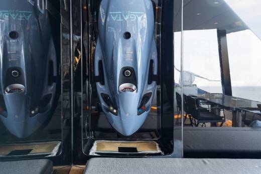 The image shows the front view of two sleek, silver-colored aircraft models or replicas displayed in a glass enclosure, with a blurred background suggesting an indoor setting.