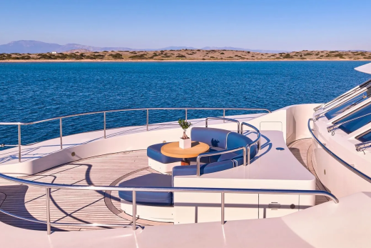 Relax on the luxurious deck of a yacht, enjoying the tranquil blue waters and distant, sun-drenched coastline.