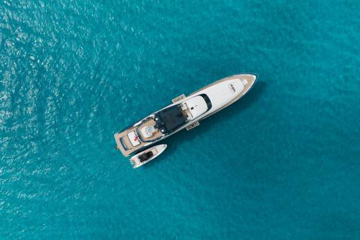 A luxurious yacht and its tender float serenely on the crystal-clear turquoise waters of the ocean.
