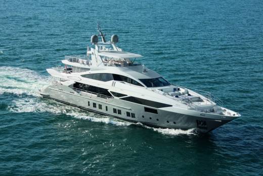 A large, luxurious yacht is sailing across the calm, blue waters of the ocean, leaving a wake behind it.