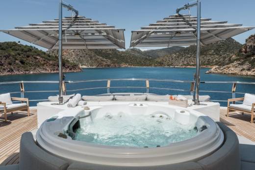 Relax in the bubbling jacuzzi on the deck of this luxurious yacht, surrounded by stunning coastal scenery.