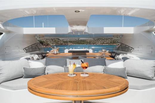 Two refreshing cocktails await on the teak table of this luxurious yacht, set against a stunning backdrop of the Mediterranean Sea.