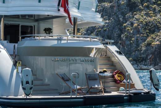 The luxurious yacht "Orient Star" rests peacefully in a sun-drenched cove, its deck ready for relaxation.