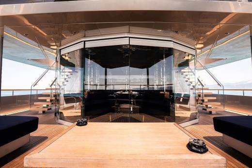 A luxurious and modern interior of a yacht, featuring a spacious deck with comfortable seating areas, a sleek design, and large windows providing a panoramic view of the surroundings.