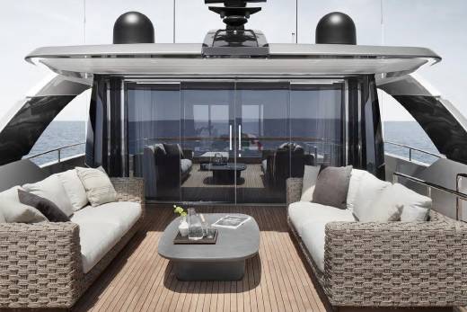A luxurious outdoor seating area on the deck of a sleek, modern yacht, overlooking the open sea.