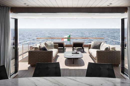 A cozy and luxurious outdoor seating area on the deck of a yacht, with a panoramic view of the vast, serene ocean in the background.