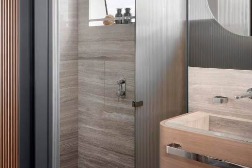 A modern bathroom with a glass shower enclosure, a wooden vanity, and a minimalist design aesthetic.