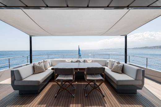A modern, open-air deck overlooking a scenic ocean view, featuring comfortable outdoor furniture and a shaded canopy.