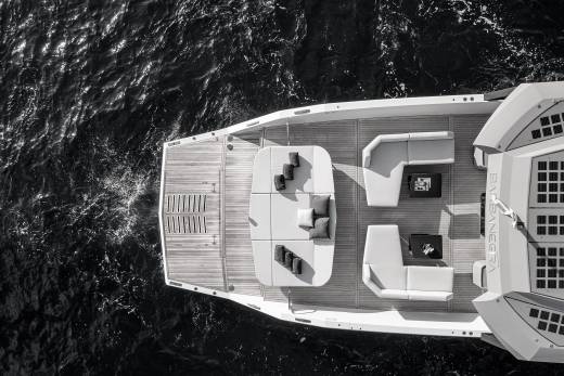A luxurious yacht with plush seating and sunbeds rests on dark, rippling water.
