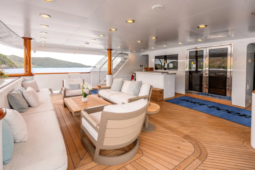 A luxurious yacht deck with comfortable seating in the foreground and a serene ocean view in the background.