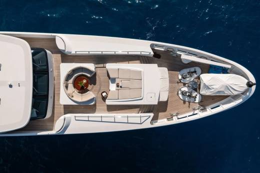 A luxurious white yacht with a spacious deck and seating areas floats on the deep blue ocean.