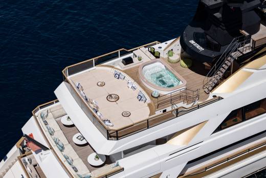 A luxurious yacht with a jacuzzi and seating areas on its deck floats on the deep blue ocean.