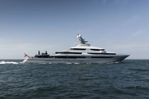 A large, modern yacht cruises on calm, blue water under a clear sky.