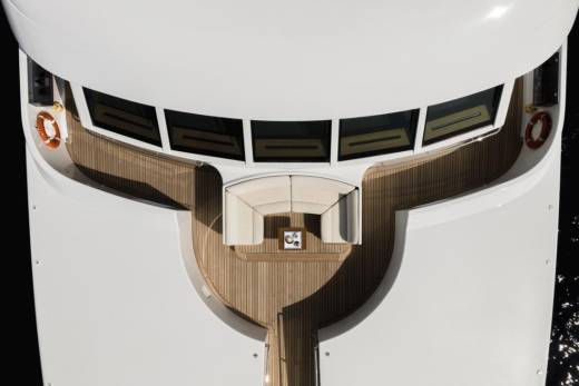 A luxurious white yacht with a wooden deck and seating area is docked in dark water.
