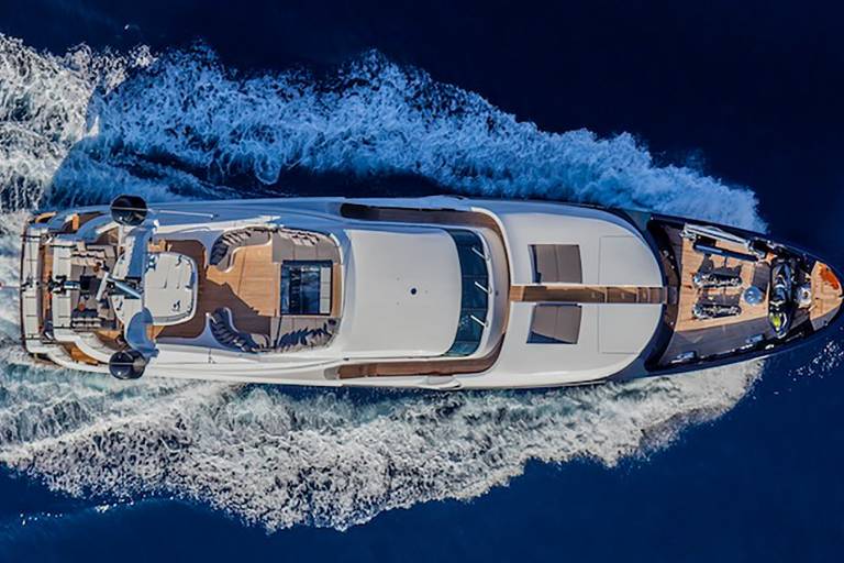 A sleek white yacht cuts through the deep blue ocean, leaving a foamy wake in its powerful wake.