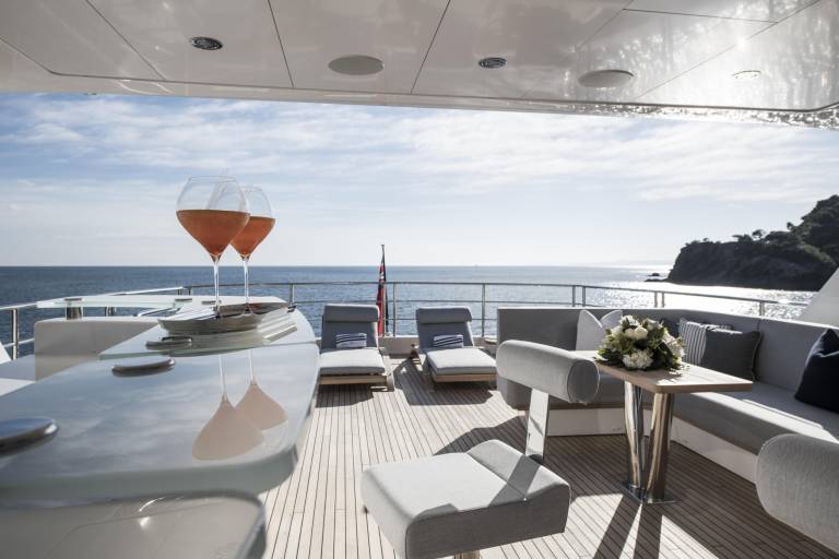 Two glasses of rosé sit on a yacht's deck, ready for enjoyment with a stunning ocean view.