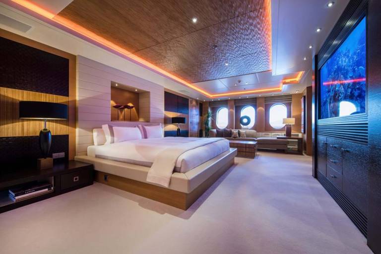 Luxurious yacht master suite features a king-sized bed, ambient lighting, and a stunning aquarium wall.