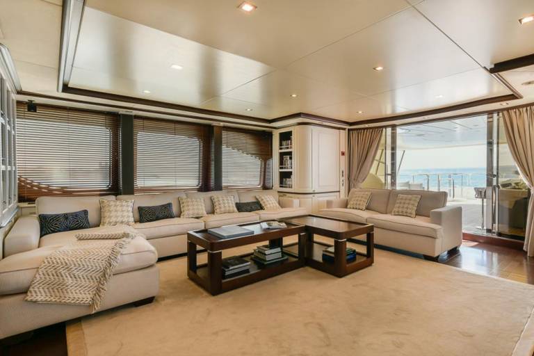 Relax in luxurious comfort within this yacht's elegant salon, offering stunning ocean views through expansive sliding doors.