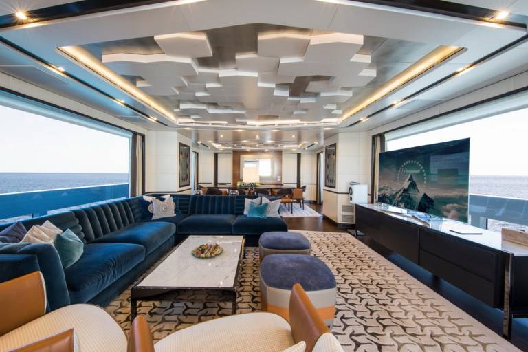 Luxurious yacht interiors offer expansive ocean views through floor-to-ceiling windows, complemented by plush seating and modern entertainment systems.