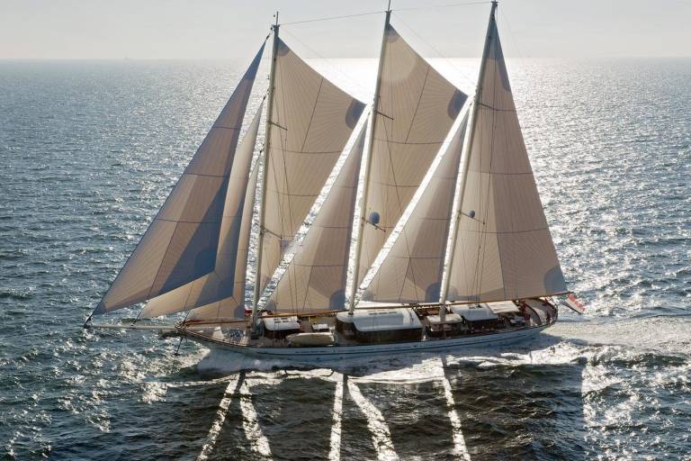 A majestic schooner glides across the sun-dappled ocean, its sails billowing in the gentle breeze.