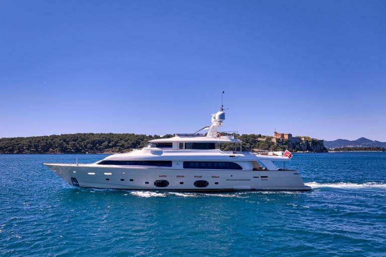 A sleek white yacht cruises through the vibrant blue waters of the Mediterranean Sea.