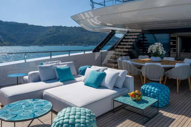 Relax on the spacious deck of a luxurious yacht, surrounded by stunning ocean views and comfortable outdoor seating.