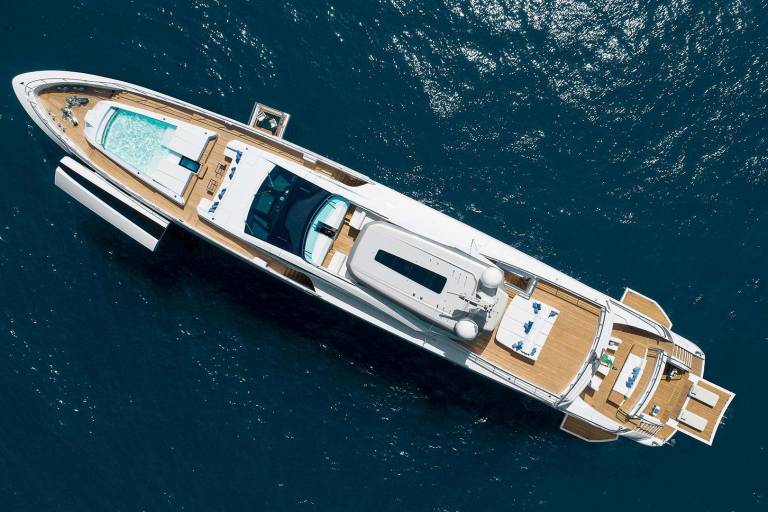 A luxurious yacht with a swimming pool and spacious deck glides through the deep blue ocean.