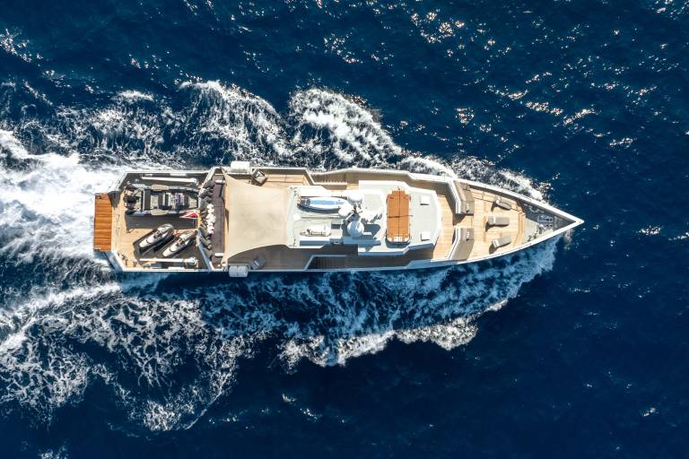 A luxurious yacht glides through the deep blue ocean, leaving a trail of white foam in its wake.