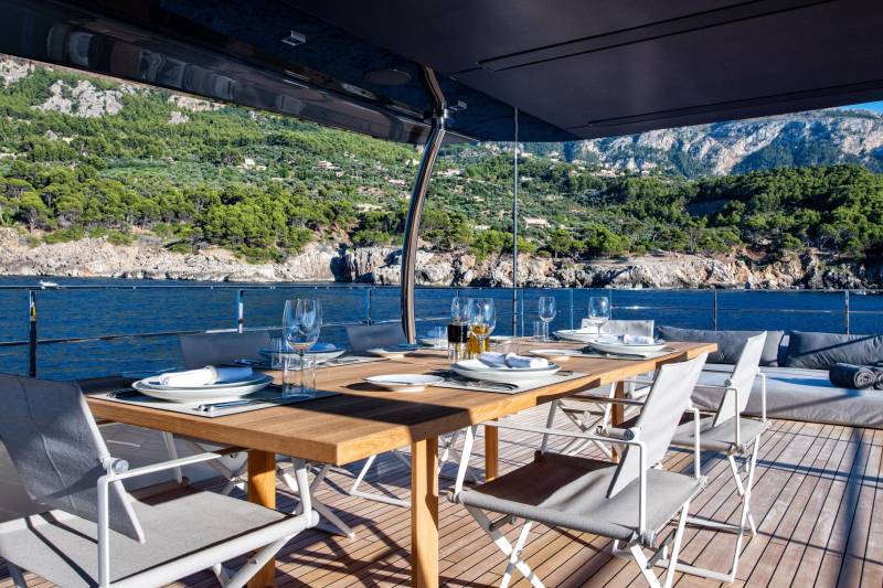 Dine al fresco on a luxurious yacht deck with a stunning backdrop of verdant Mediterranean hillsides.