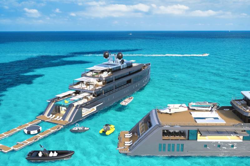 A large luxury cruise ship is anchored in the crystal-clear turquoise waters of a tropical paradise, surrounded by smaller boats and water activities.