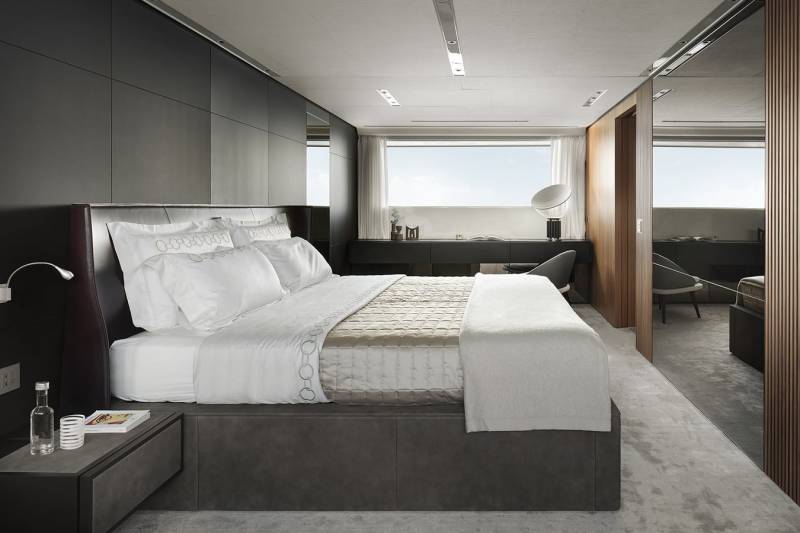 Luxurious modern bedroom with a large bed, sleek dark cabinetry, and expansive window views.