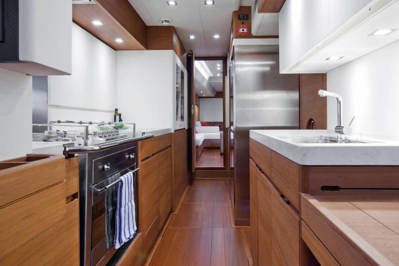 A sleek, modern galley kitchen with rich wood cabinetry and stainless steel appliances offers a functional and stylish space on board.
