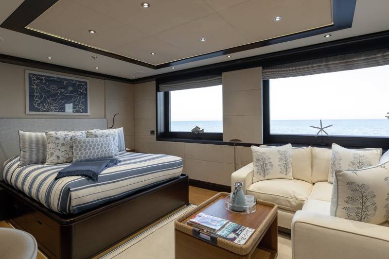 A luxurious yacht cabin offers a serene retreat with ocean views, plush bedding, and comfortable seating.