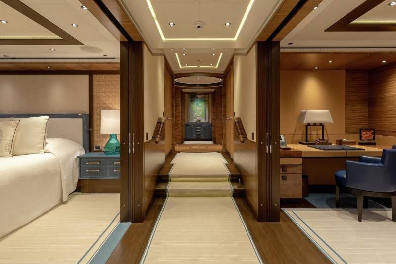 Luxurious wood paneling and plush carpets create an opulent hallway leading to a well-appointed bedroom and office.