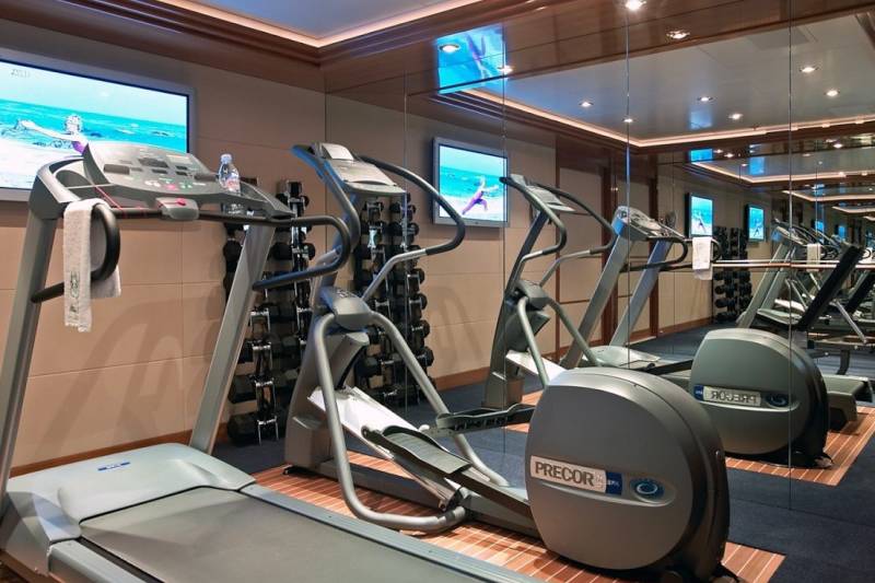 This well-equipped gym features treadmills, ellipticals, and a mirrored wall reflecting the workout space.