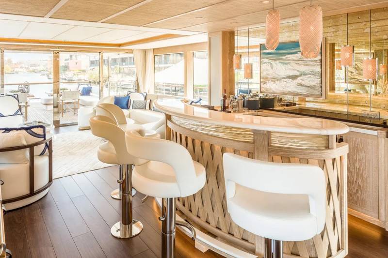 Luxurious bar stools and a sleek counter invite guests to enjoy drinks with a view of the tranquil waterway.