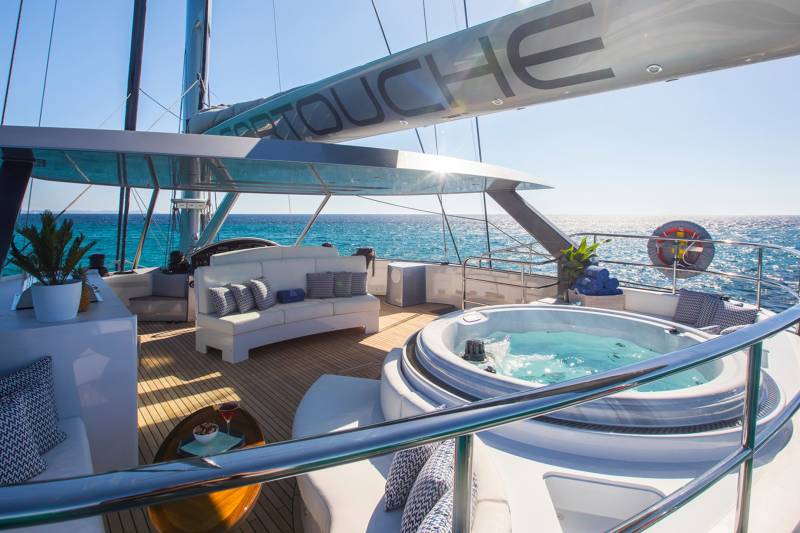 Relax in the onboard jacuzzi while sailing the azure waters under a clear blue sky.