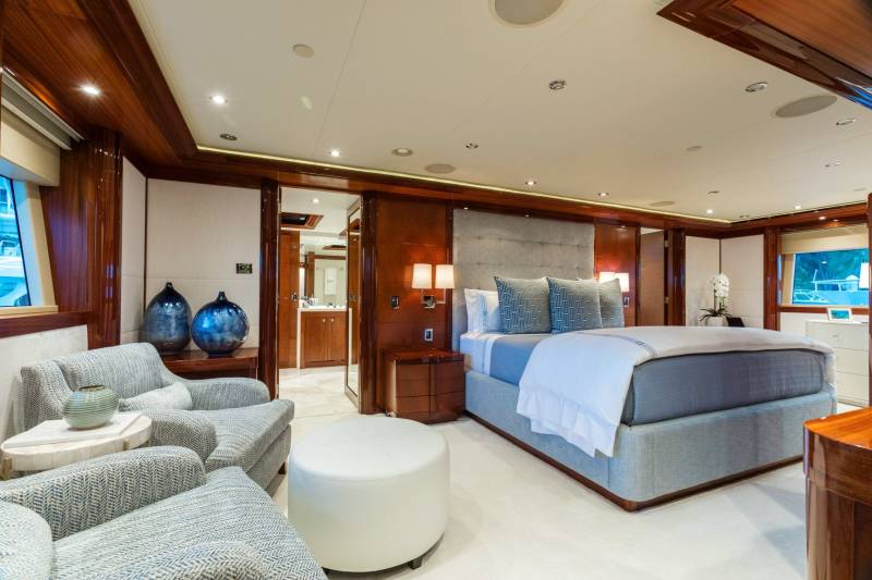 Luxurious yacht accommodations feature a plush king-sized bed, elegant seating, and a glimpse into the en-suite bathroom.