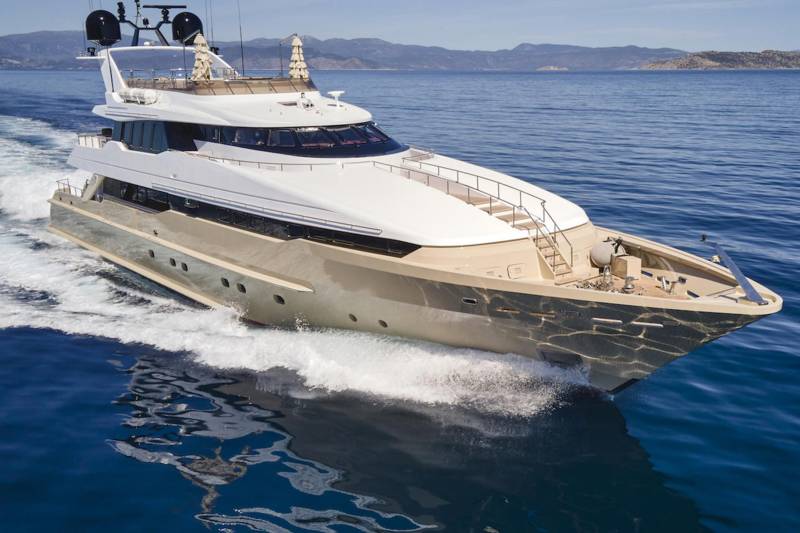 A sleek, modern yacht cuts through the deep blue sea, leaving a foamy wake under a clear sky.