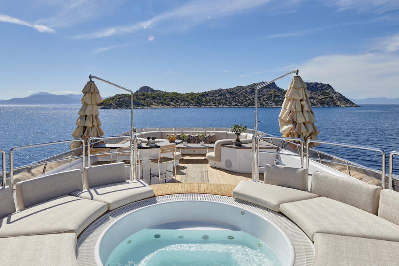 Relax in the bubbling hot tub on the deck of this luxurious yacht, surrounded by the stunning blue sea and distant islands.