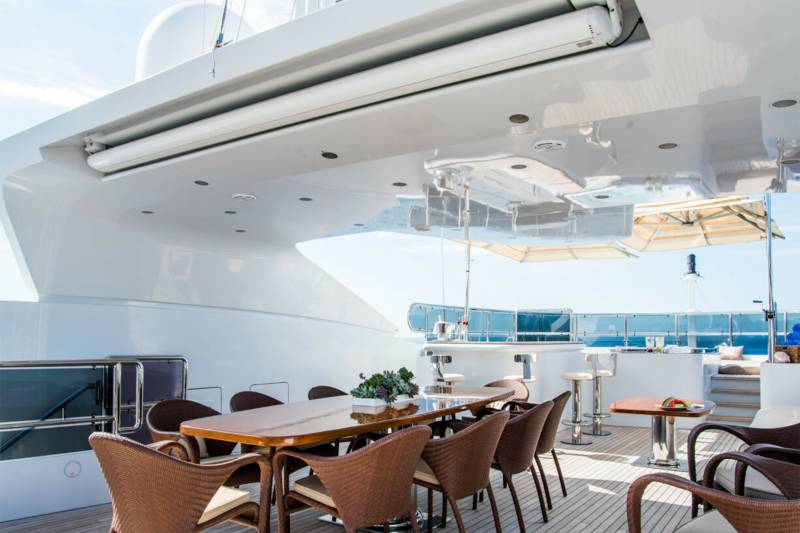 Enjoy al fresco dining and cocktails on the deck of this luxurious yacht under a bright blue sky.