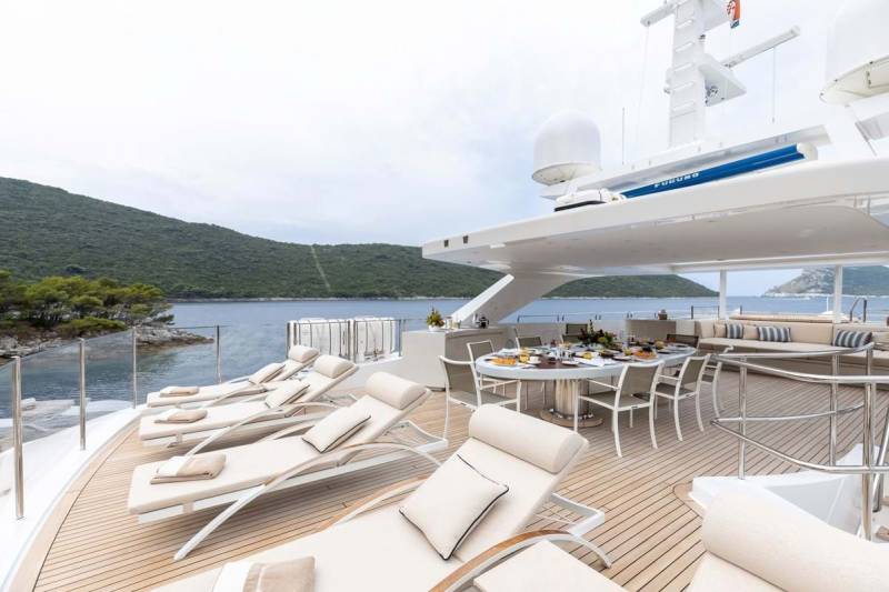 Relax on the deck of a luxurious yacht, surrounded by stunning coastal scenery and the calm blue sea.