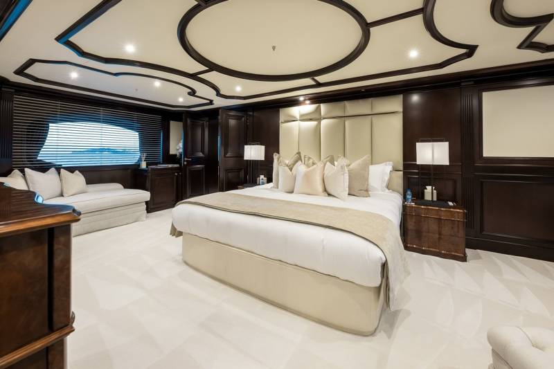 Luxurious dark wood paneling and a plush bed create an opulent sanctuary on this elegant yacht.
