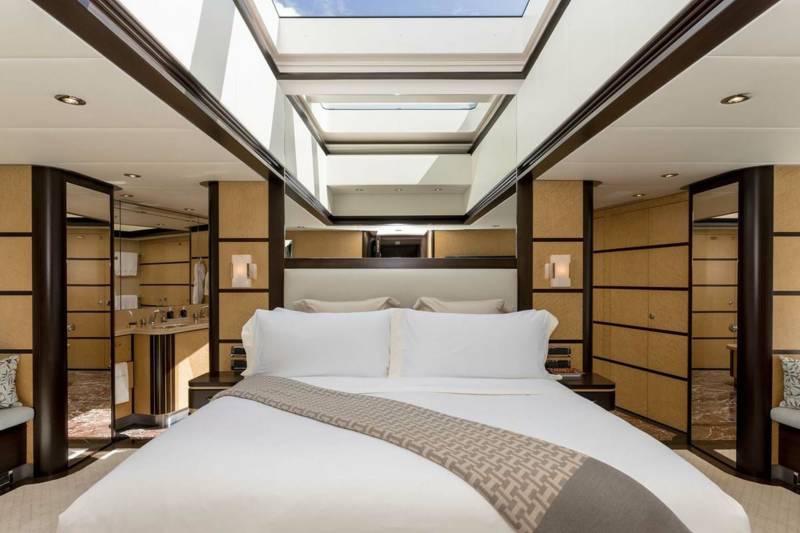 Luxurious yacht bedroom features a king-size bed, skylights, and an en-suite bathroom with marble floors.