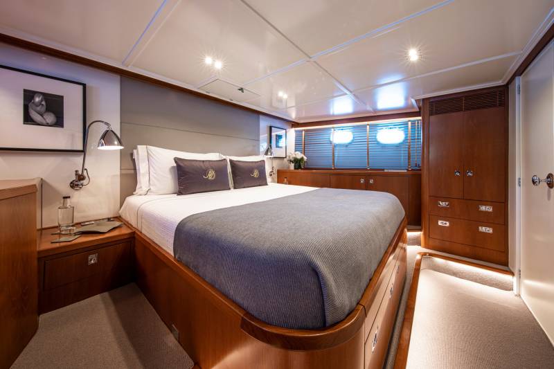Luxurious yacht cabin features a plush king-sized bed, elegant wood cabinetry, and ambient lighting for ultimate comfort.