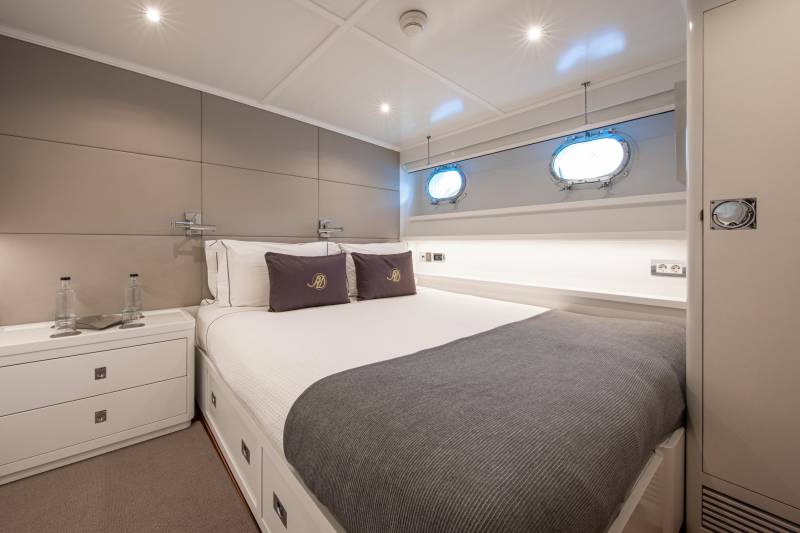 Luxurious yacht cabin features a comfortable bed, porthole windows, and ample storage for a serene maritime escape.