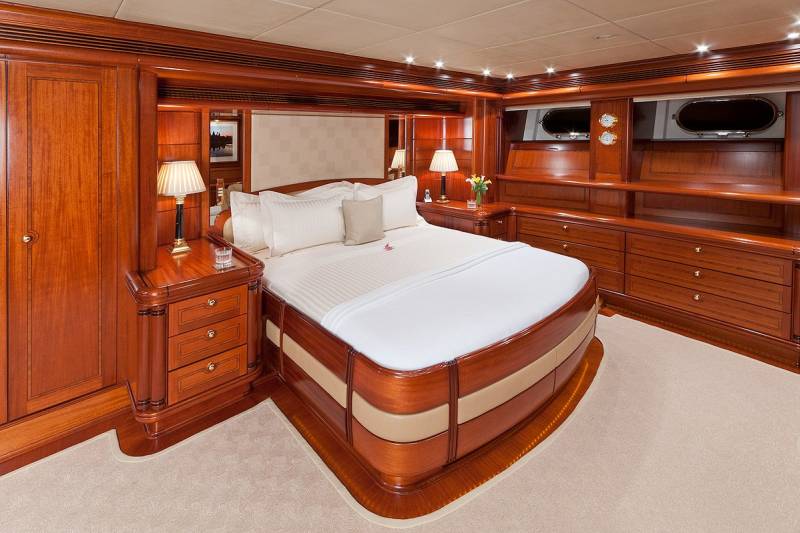 Luxurious cherry wood cabinetry and a plush bed create a serene and elegant master suite on this yacht.
