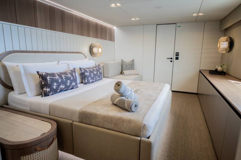 A luxurious yacht cabin features a plush bed, modern lighting, and elegant wood accents for ultimate comfort at sea.